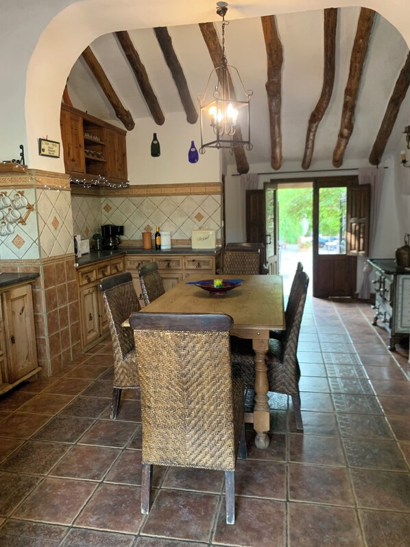 Una cucina rustica con un tavolo e sedie in legno, una moka e un lampadario.
