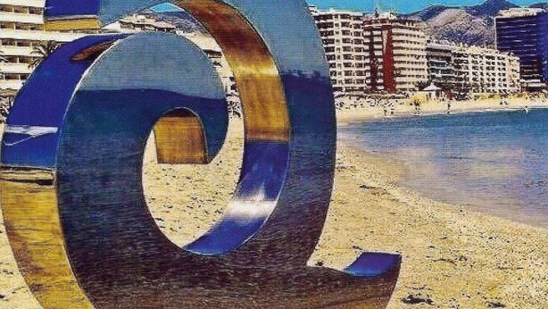 A large metallic 'O' sculpture on a white base, located on a sandy beach with buildings and mountains in the background. - APARTMENT NEXT TO THE BEACH AND IN THE CENTER OF FUENGIROLA (Fuengirola)