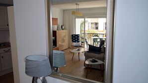 A living room with a sofa, coffee table, and a chair with a star-patterned cushion. A large mirror reflects the room and a balcony with outdoor furniture. - APARTMENT NEXT TO THE BEACH AND IN THE CENTER OF FUENGIROLA (Fuengirola)