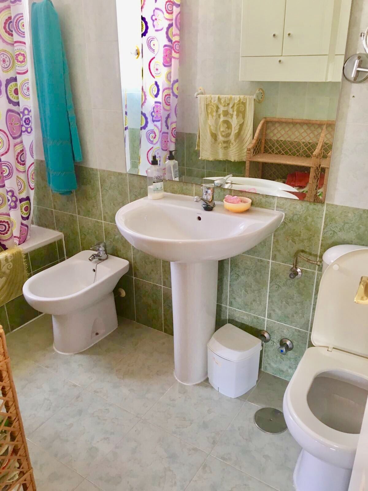 A bathroom with a pedestal sink, a bidet, a toilet, and a small wicker basket.