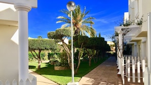 A pathway flanked by white picket fences, leading to a building with a white facade and a balcony. - Spacious 2 Bed With Great Pool Near Beach & Golf (Las Marinas Garrucha)