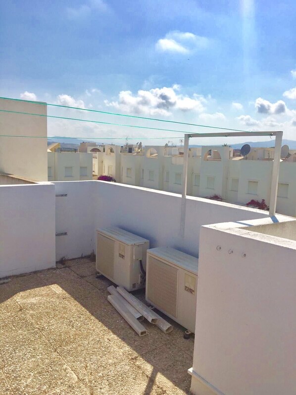 A rooftop with white buildings, a clear sky, and construction materials.