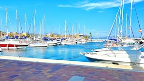 A marina with multiple boats docked, a clear blue sky, and a tiled walkway. - Spacious 2 Bed With Great Pool Near Beach & Golf (Las Marinas Garrucha)
