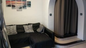 A modern living room with a black sofa, striped pillows, and a wall-mounted art piece.