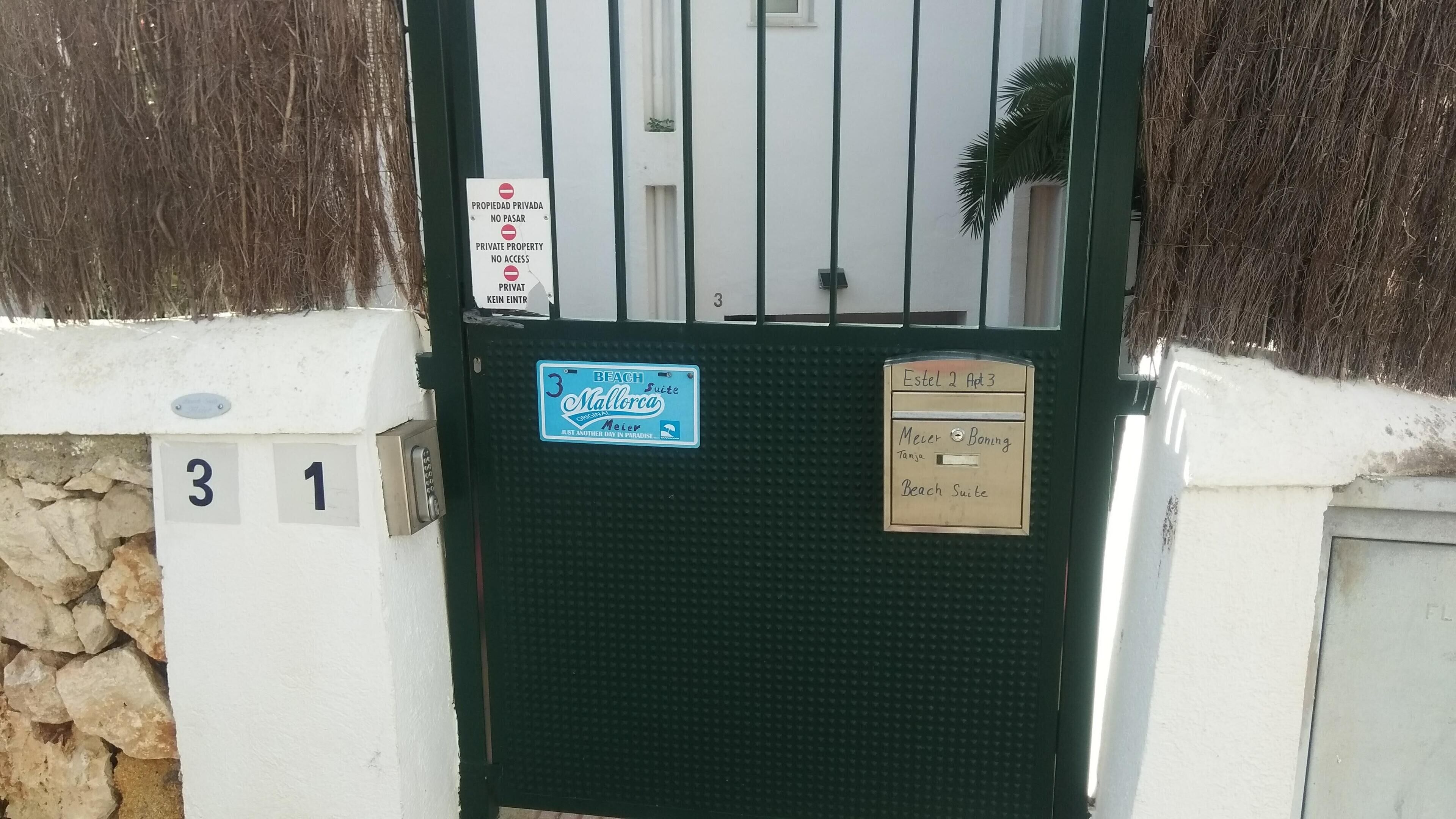 Una entrada cerrada con un letrero que indica propiedad privada y prohibido el acceso. Hay letreros numerados '3' y '1' en la pared, y un letrero azul para 'Beach Suite' con temática playera.