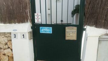 Una entrada cerrada con un letrero que indica propiedad privada y prohibido el acceso. Hay letreros numerados '3' y '1' en la pared, y un letrero azul para 'Beach Suite' con temática playera.