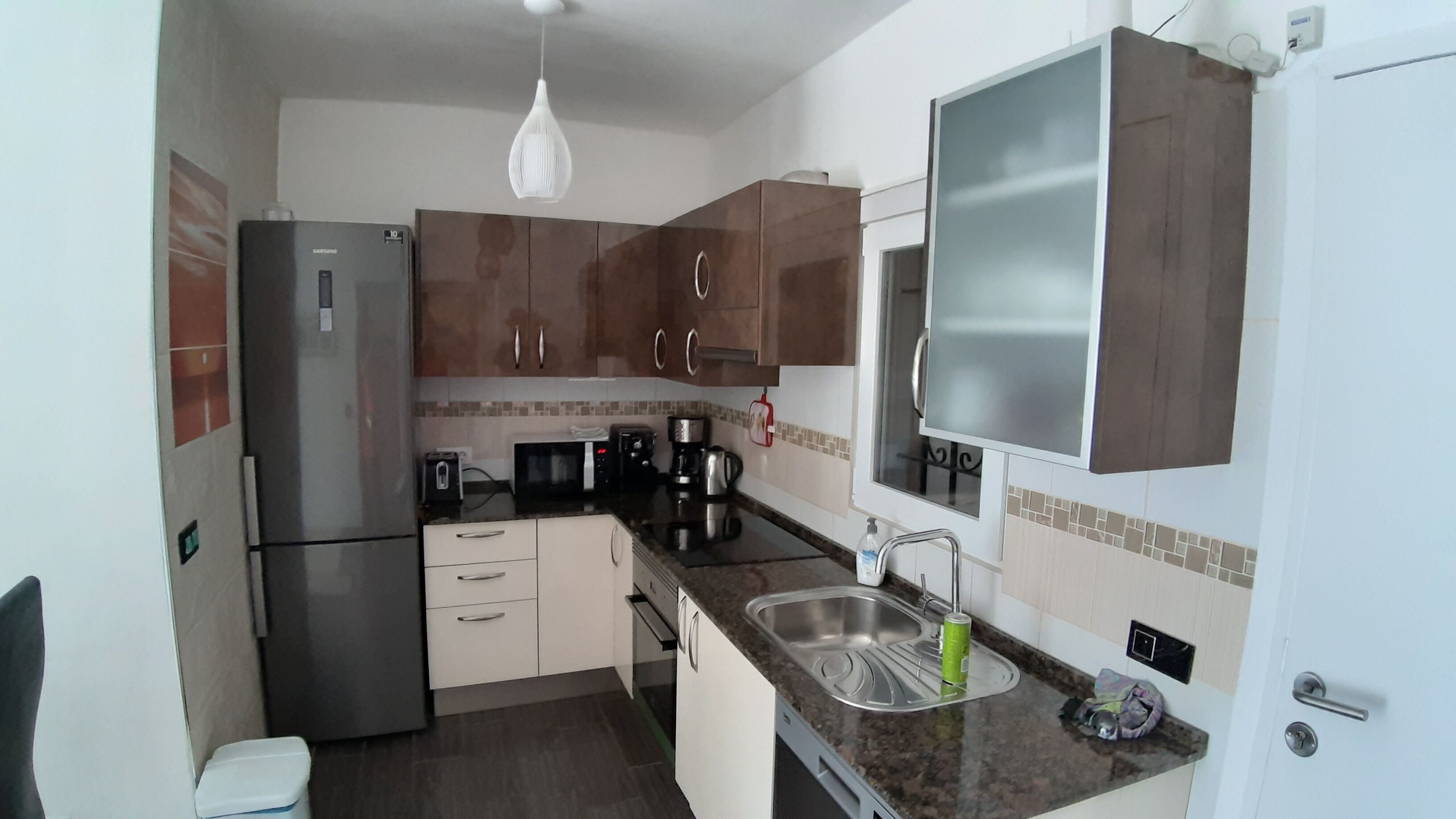 Eine kompakte Küche mit Kühlschrank, Mikrowelle, Toaster, Kaffeemaschine und Spüle.