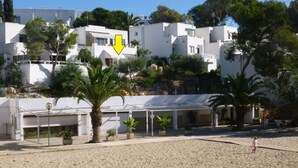A coastal building with a white facade, a visible arrow pointing to a specific area, and a sandy beach in the foreground.