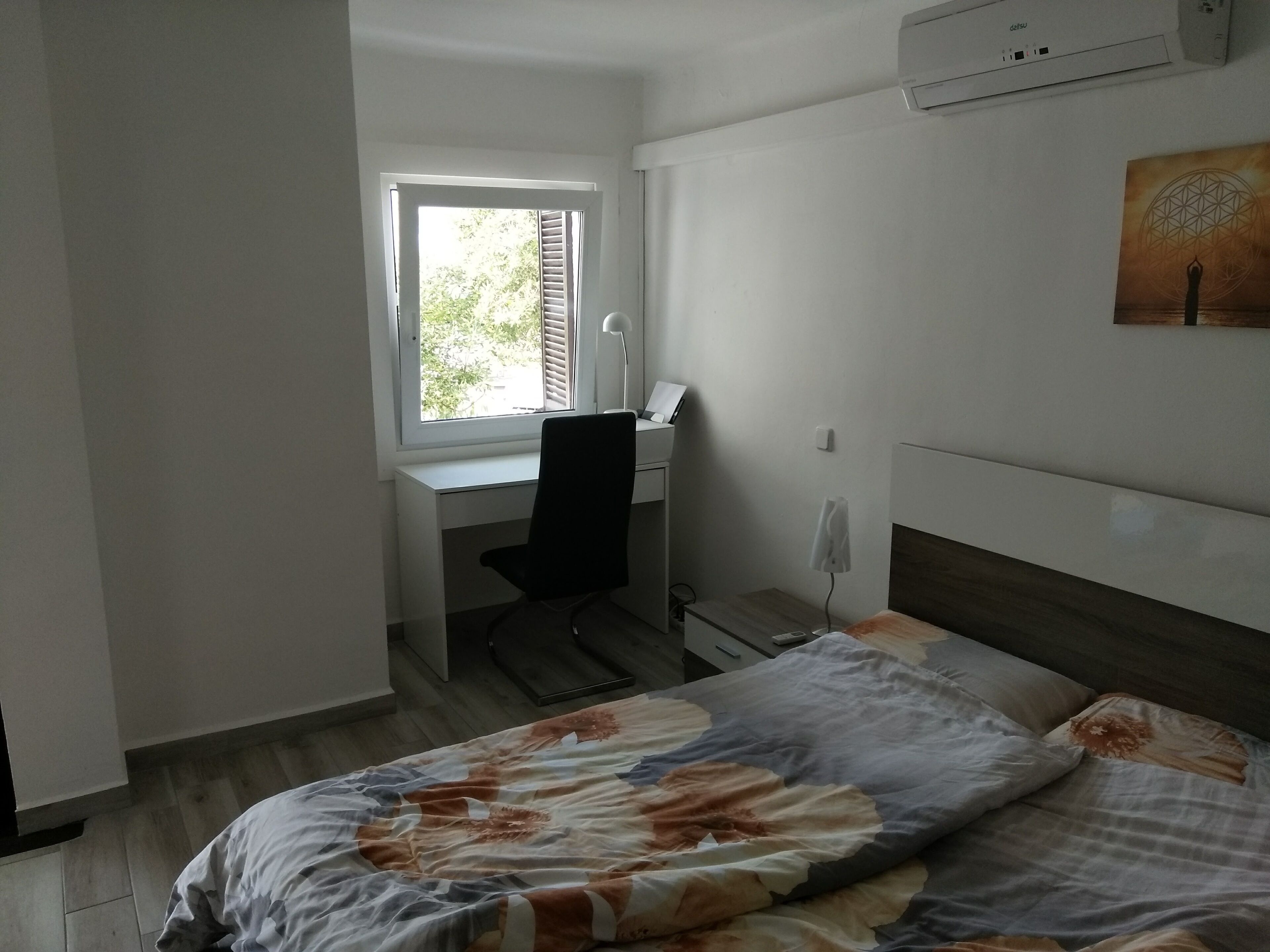 Un dormitorio con cama, escritorio y ventana.