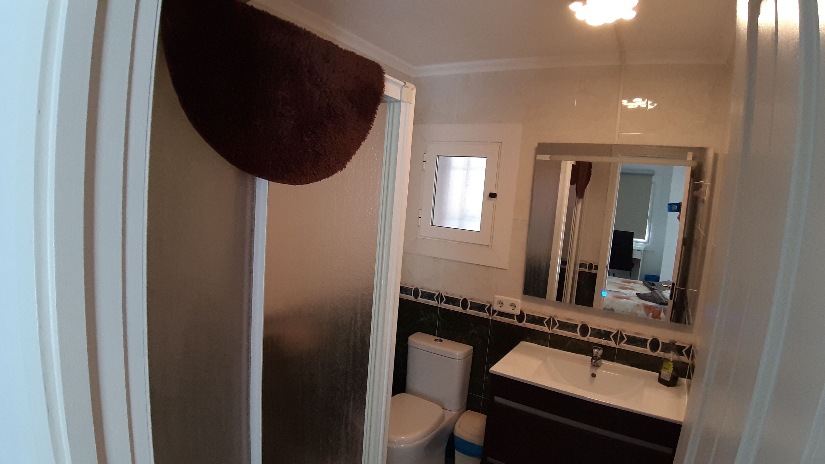 A bathroom with a toilet, sink, and mirror.