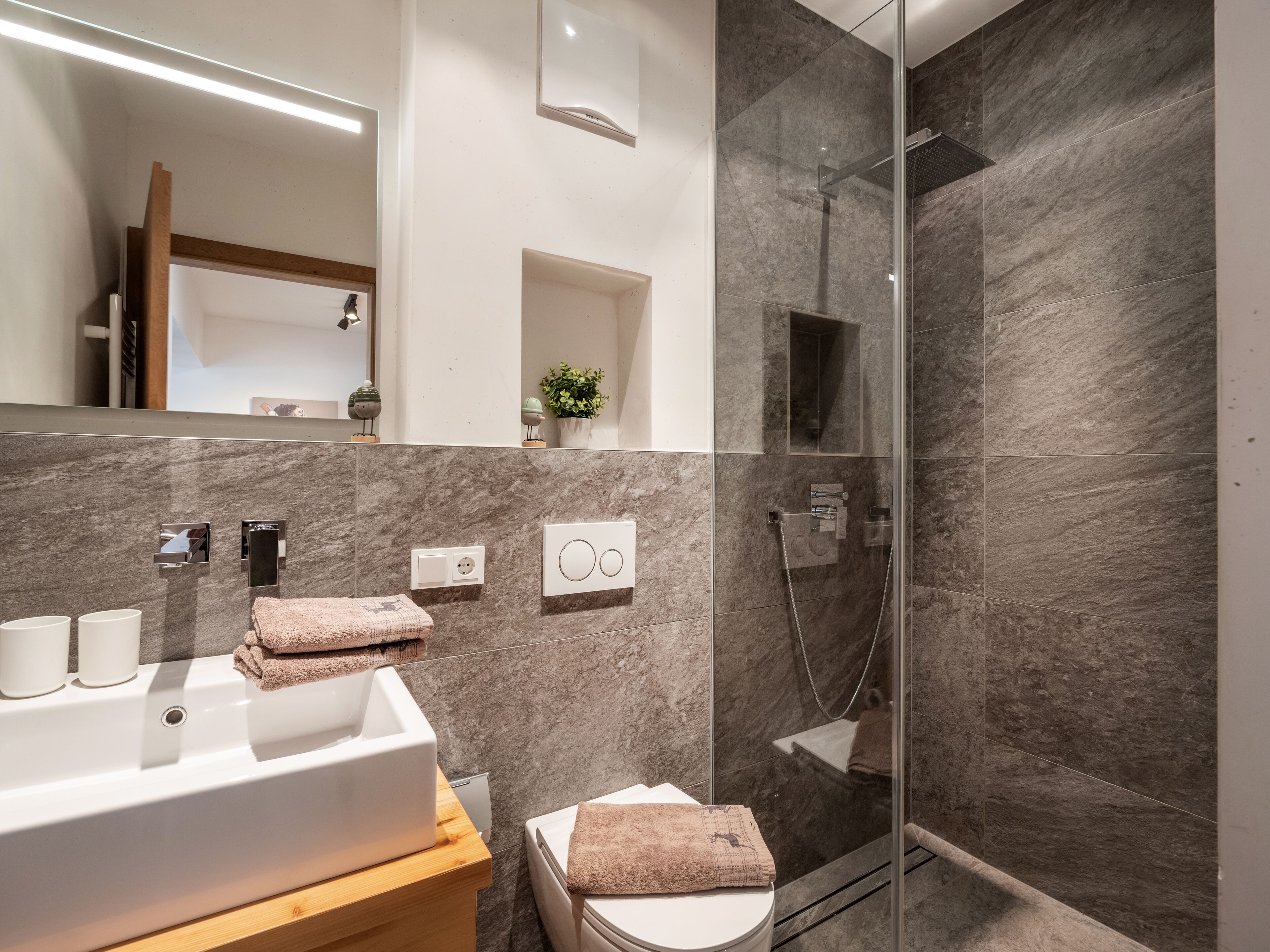 Un baño moderno con un lavabo grande, espejo y zona de ducha.