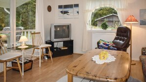 Una sala de estar acogedora con una mesa de centro de madera, un televisor, un sillón de cuero y una ventana con cortinas.