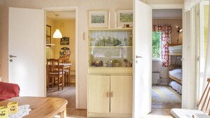 Una habitación acogedora con una mesa de madera, un armario pequeño y una cama doble con cortina estampada.
