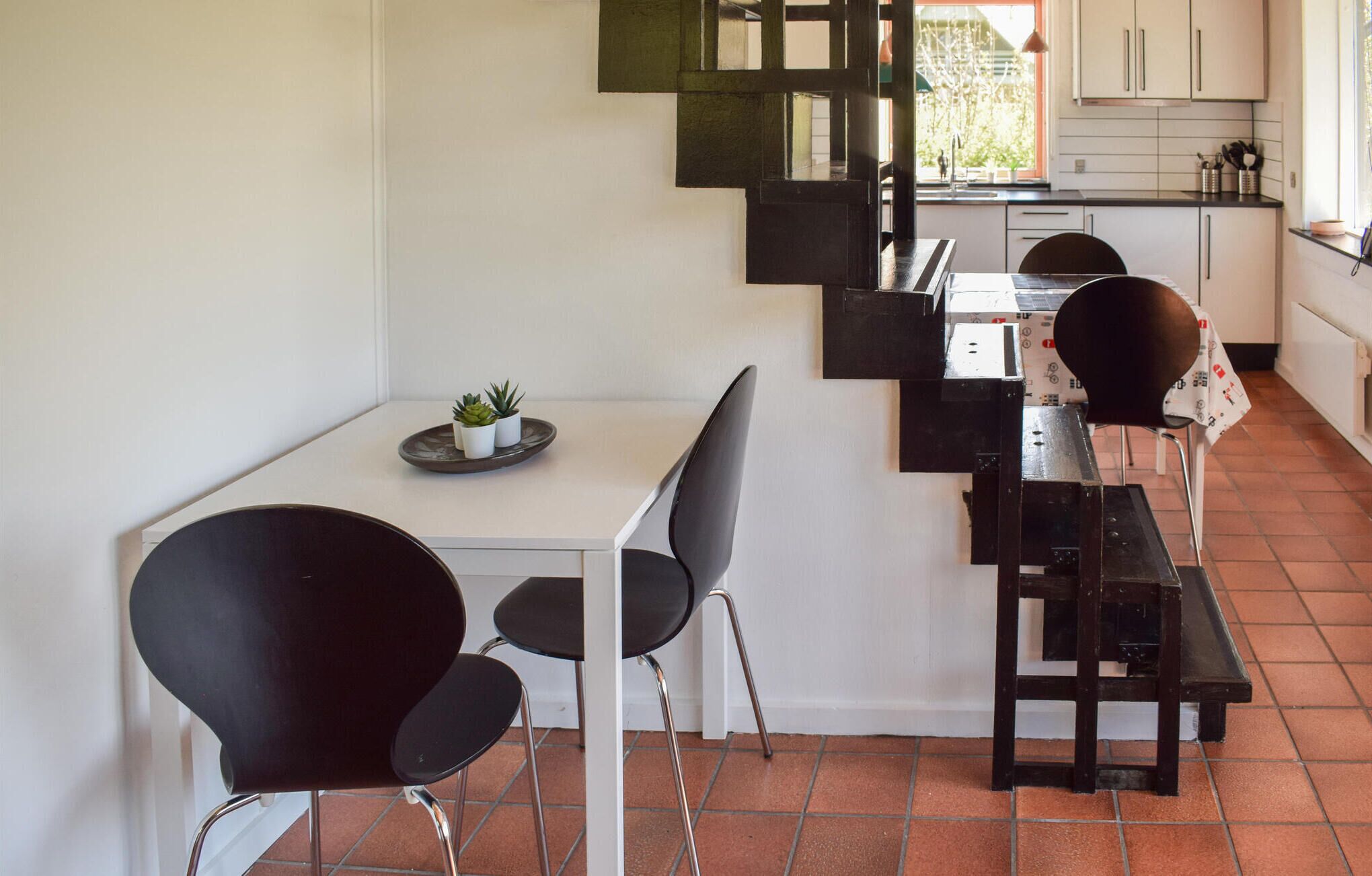 A modern kitchen with white cabinets, a black countertop, and a dining area with a white table and black chairs.