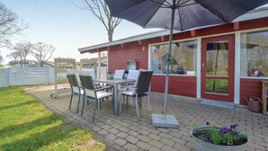 Eine Terrasse im Freien mit Tisch, Stühlen, einem großen Sonnenschirm und einem Blumentopf.