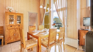 A wooden interior with a dining table, chairs, a cabinet, a radiator, and a television. - Stunning home in Rechlin with sauna (Rechlin)