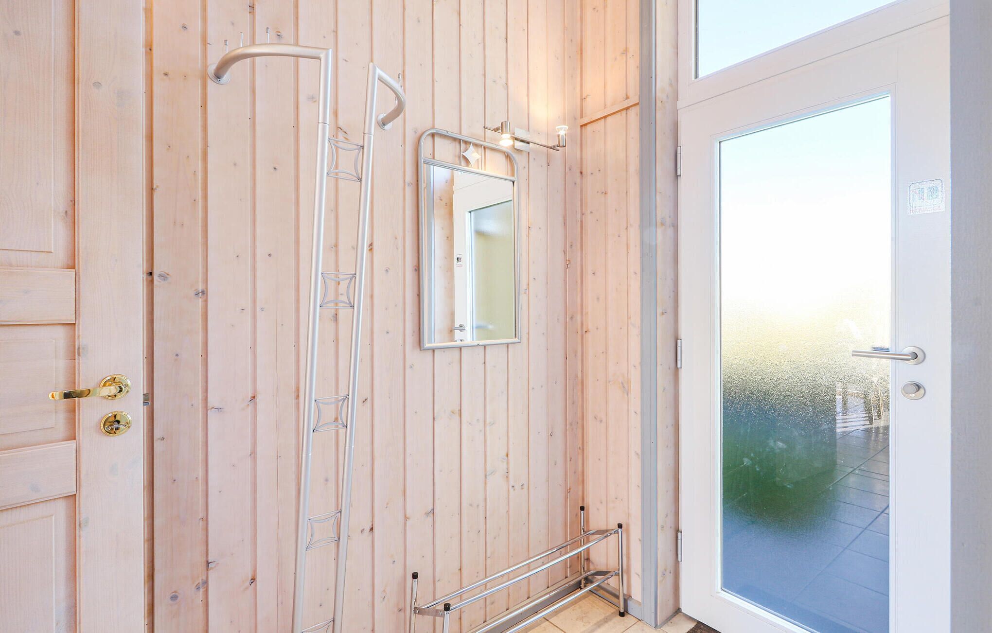 Un intérieur en bois avec une douche, un miroir et une porte en verre donnant sur l’extérieur.
