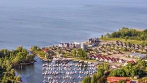 Eine Luftaufnahme eines Yachthafens mit vertäuten Booten, umgeben von Wohngebäuden und viel Grün.