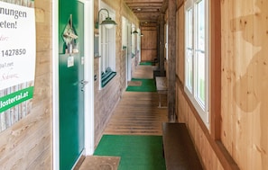 A wooden hallway with green walls, a green carpet, and a sign on the left.