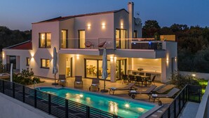 Une maison moderne à deux étages, dotée d’une piscine, d’un espace salon extérieur et d’un balcon.