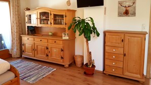 Ein Wohnzimmer mit Holzmöbeln, einem Flachbildfernseher, einem Blumentopf und einem Bild eines Rehs an der Wand.