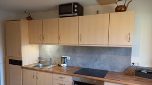 Eine moderne Küche mit Holzausbau, einer Edelstahl-Spüle, einem Wasserkocher und einem Toaster.