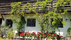 Ein rustikales Gebäude mit einem Strohdach, Holzbalken und einem Balkon mit Kletterpflanzen.