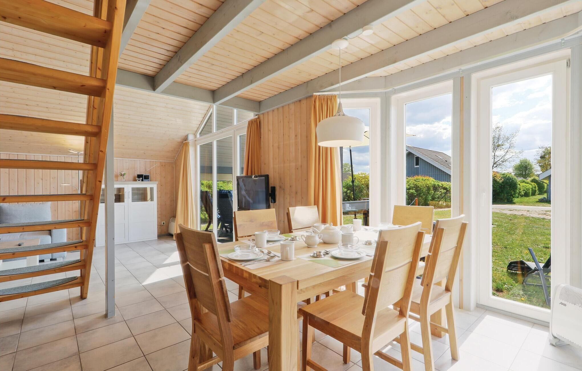 A spacious dining area with a wooden table and chairs, a television, and a view of the garden through large windows.