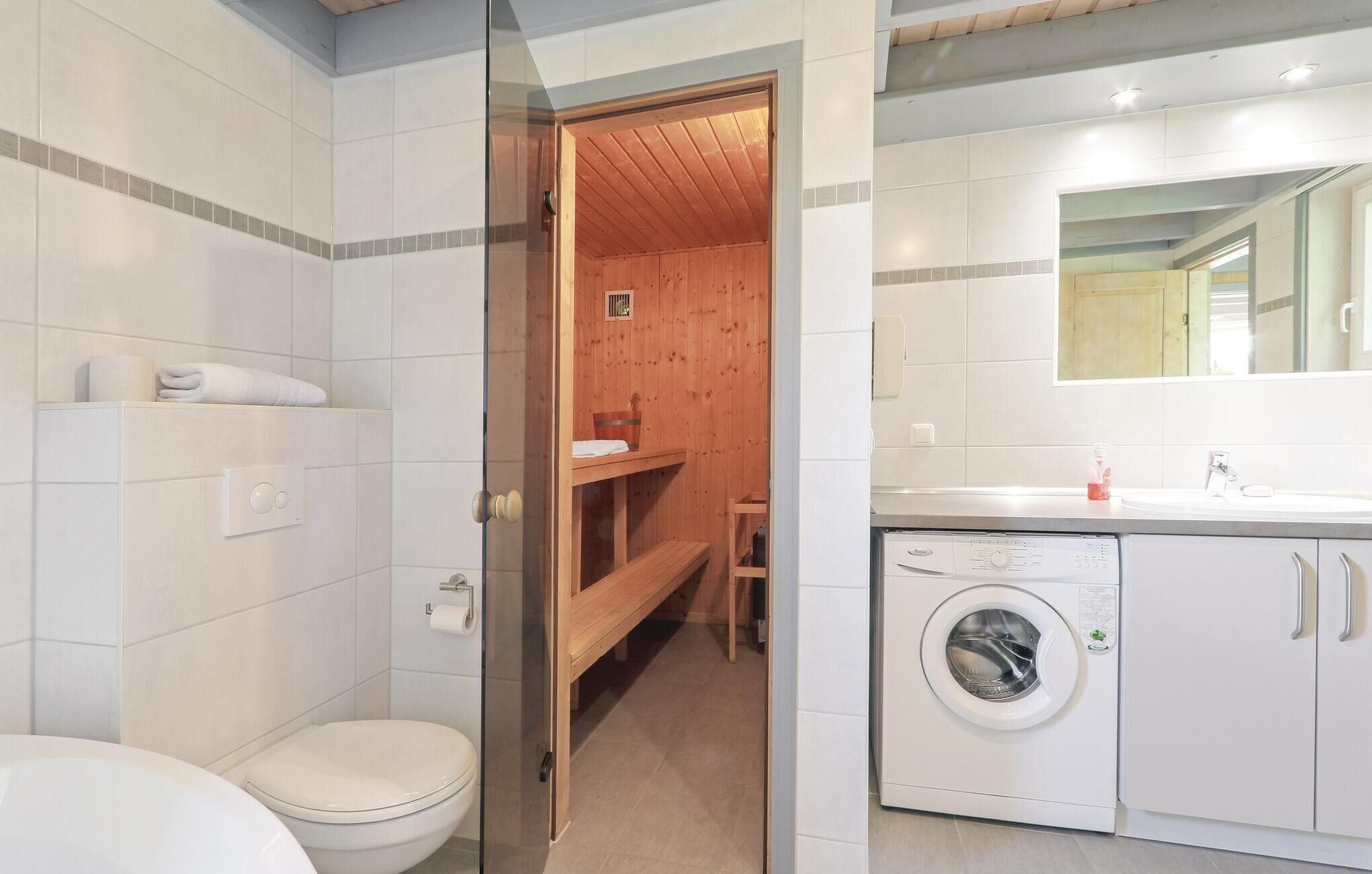 Une salle de bain moderne équipée de toilettes, d’un lave-linge et d’un sauna en bois.