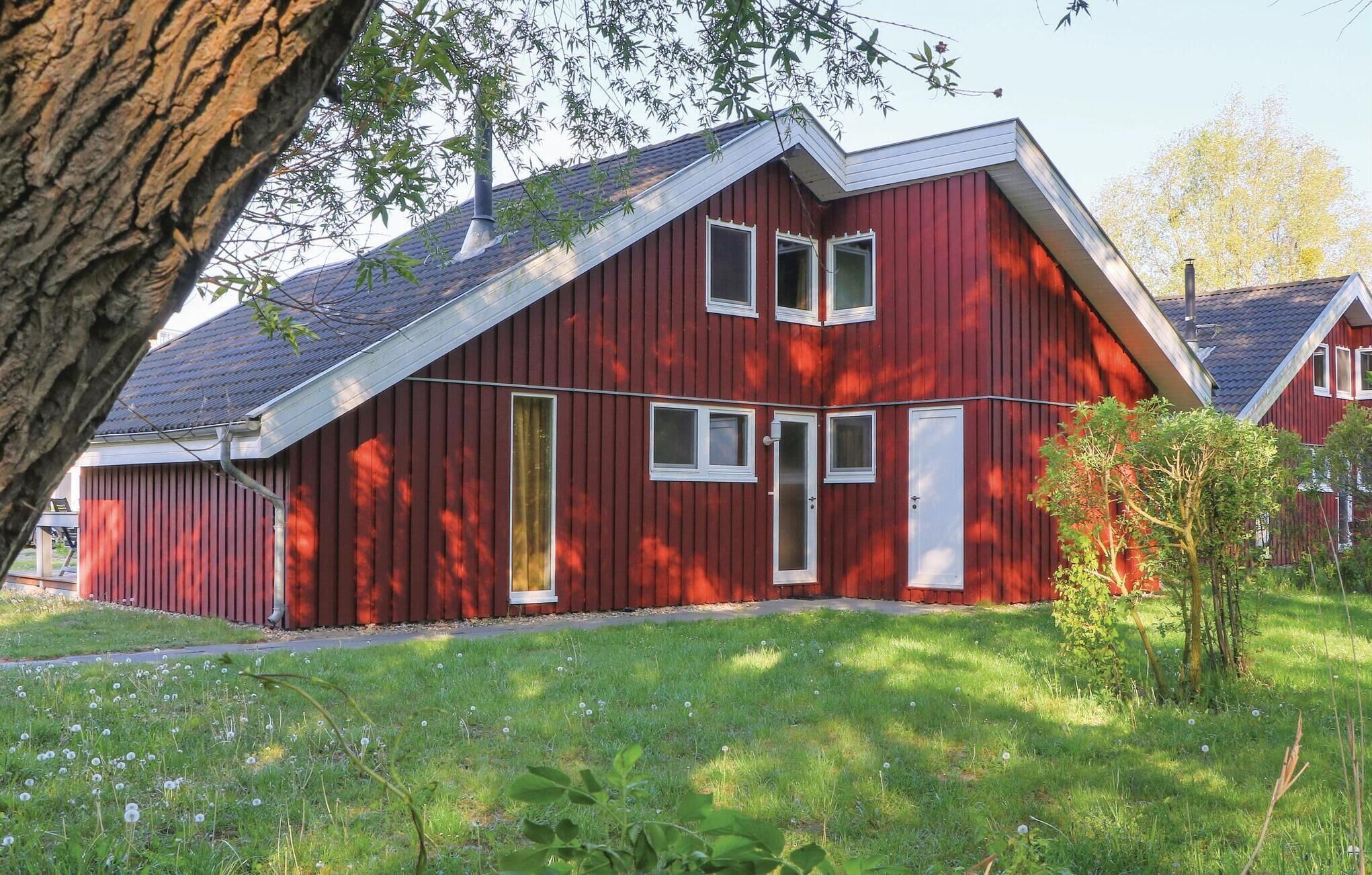 Ein rotes Holzhaus mit geneigtem Dach, einer Haustür und einer kleinen Veranda.