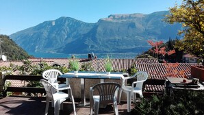 A terrace with a table and chairs overlooking a mountainous landscape and a body of water. - Holiday feeling Lake Garda Limone  (Pieve)