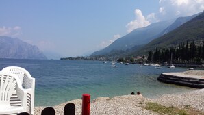 A lakeside view with boats, mountains, and a chair by the water. - Holiday feeling Lake Garda Limone  (Pieve)