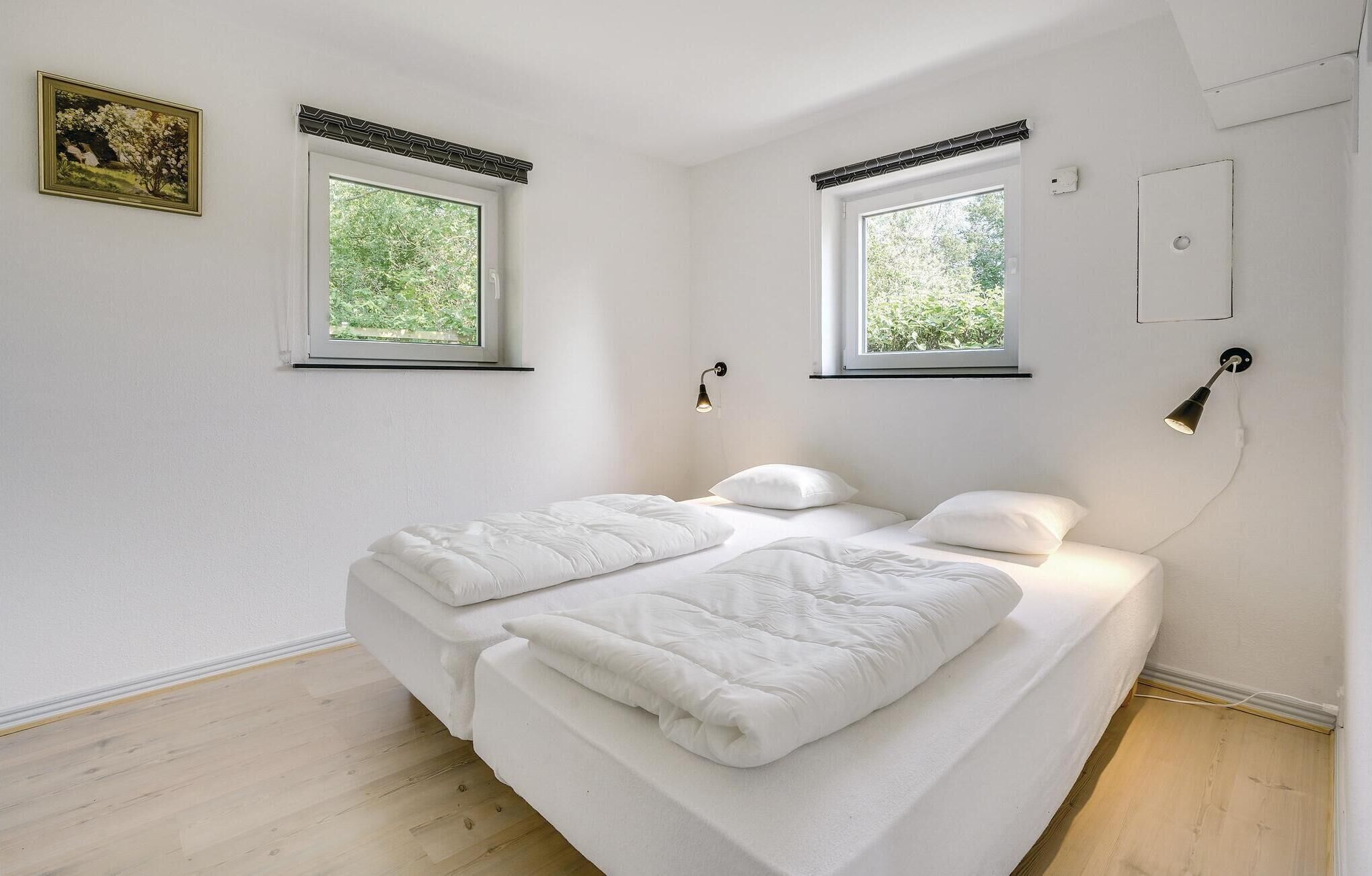 Een slaapkamer met een bed, twee ramen en een wandlamp.