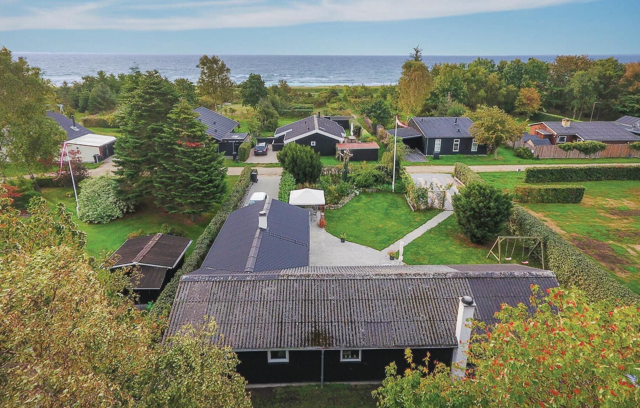 Ett bostadsområde med hus, en gräsyta och utsikt över havet.