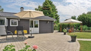 Una casa con un patio que incluye una zona de estar techada, una silla y una maceta.