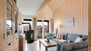 A cozy living room with a wooden interior, a sofa, a table, and a television. - Nice apartment in Rechlin with WiFi (Rechlin)