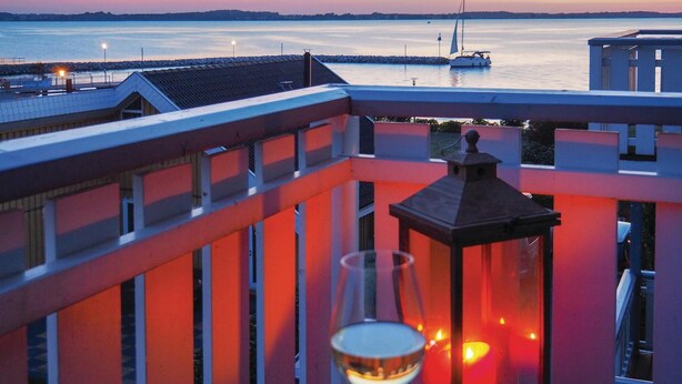 A balcony with a view of a calm body of water and a sailboat. - Nice apartment in Rechlin with WiFi (Rechlin)