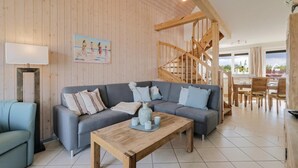 A modern living room with a grey sofa set, a wooden coffee table, and a wooden staircase. - Nice apartment in Rechlin with WiFi (Rechlin)