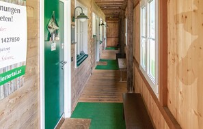 A wooden hallway with green walls, a green carpet, and a sign on the left.