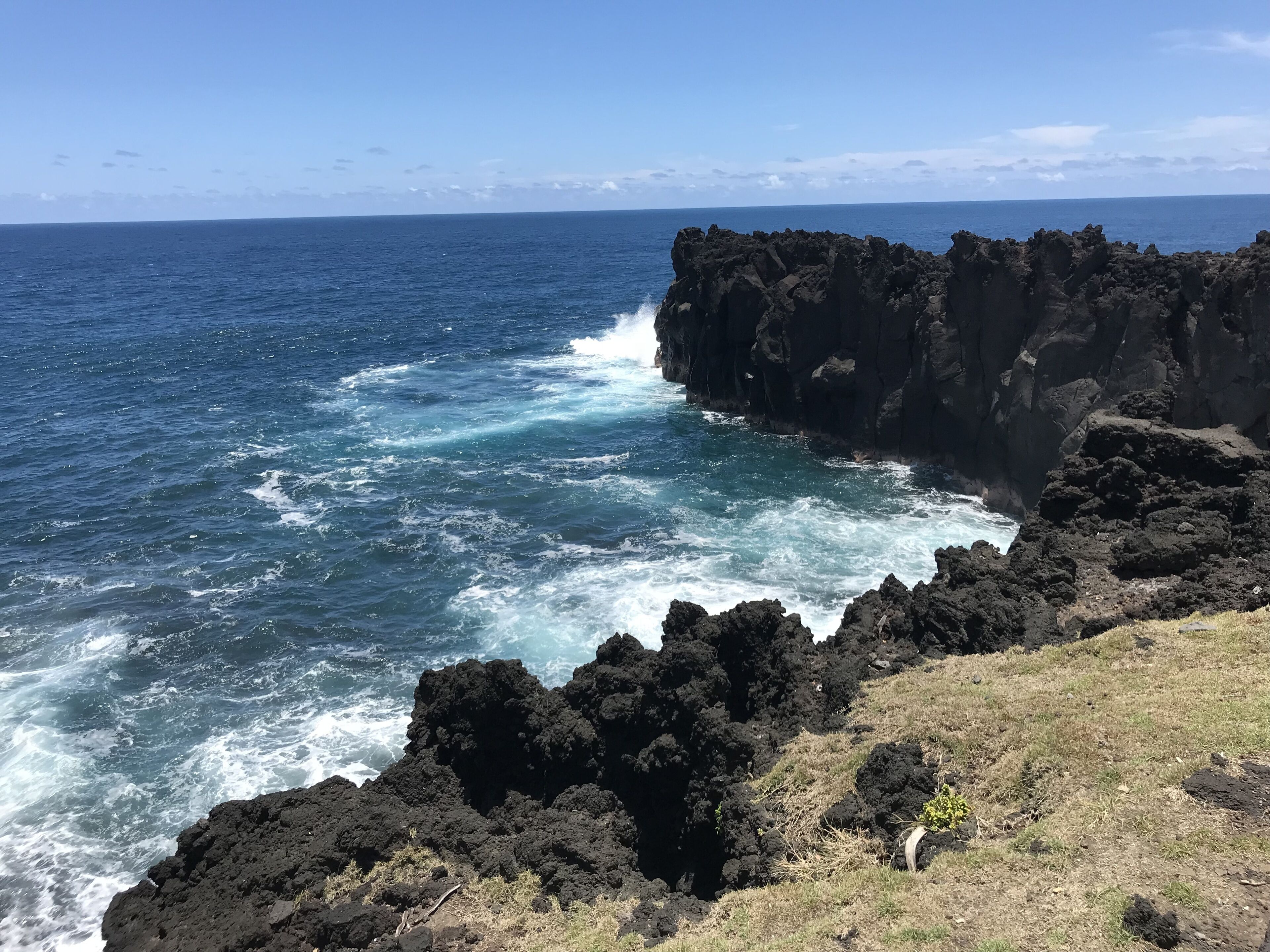 A coastal landscape with dark volcanic rocks and the ocean.