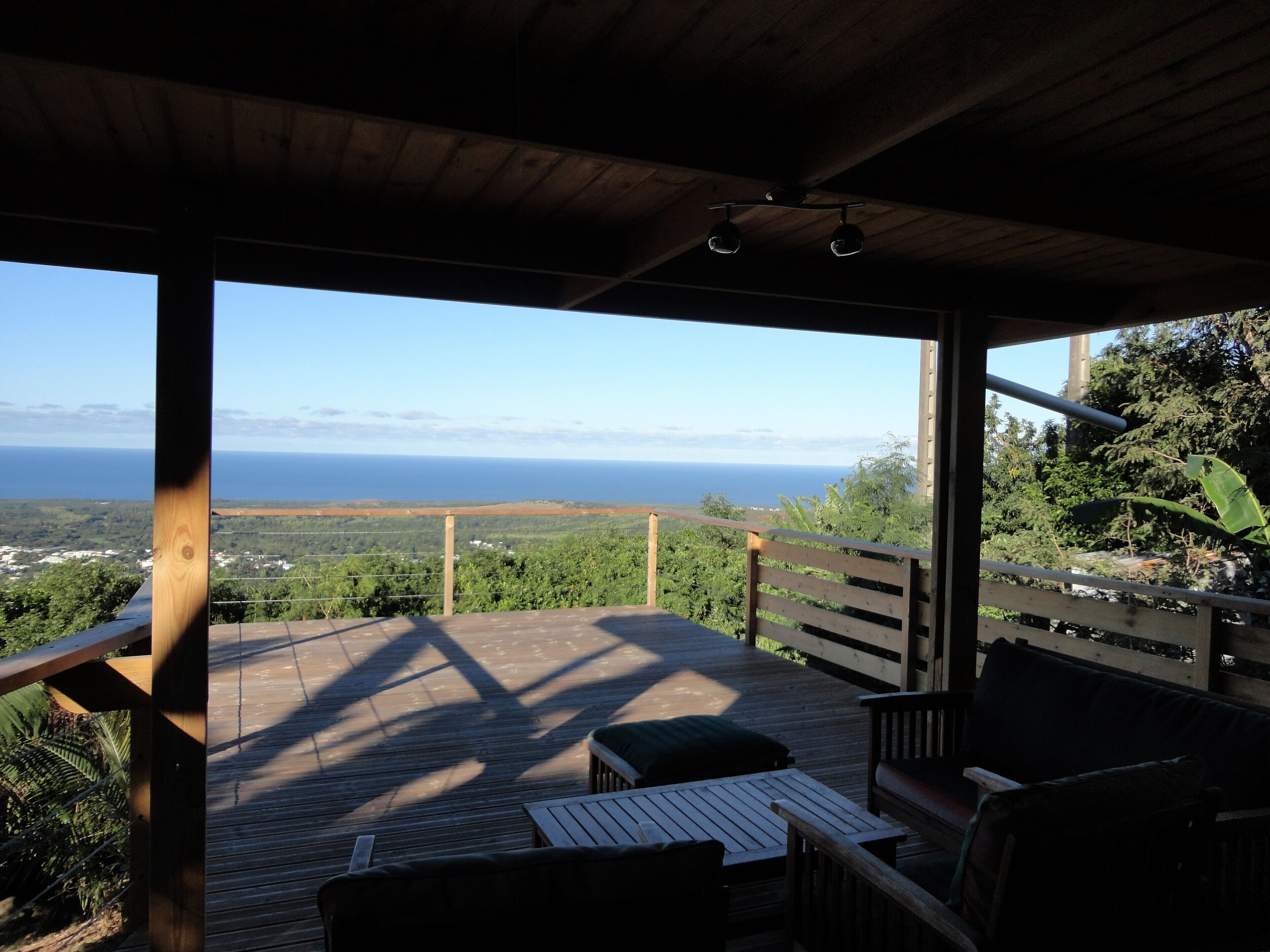 A wooden deck with a view of the ocean, a wooden bench, and a table.