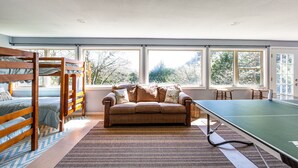 A room with bunk beds, a sofa, and a ping pong table.