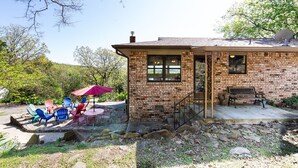 A rustic stone building with a brick exterior, a covered patio with outdoor seating, and a satellite dish on the roof.