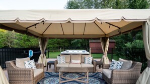 An outdoor patio area with wicker furniture, a central table, and a patterned rug. - Close to BROADWAY BNA-Gorgeous Home - Idyllic Countryside, Heated Pool & Hot Tub (Mt Juliet)