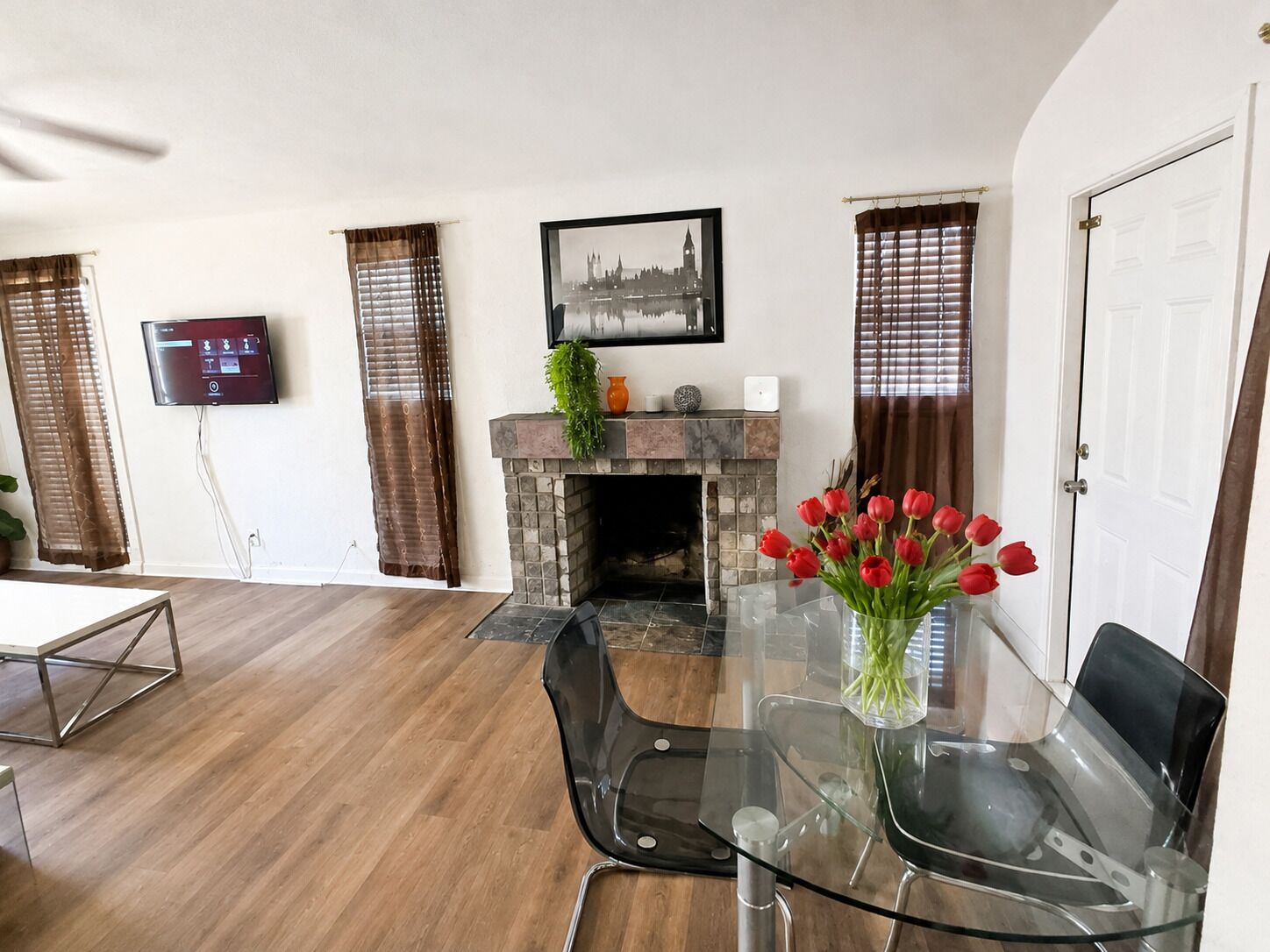 A modern living room with a fireplace, a dining table, and a TV mounted on the wall.