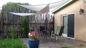 A patio area with a table and chairs, a blue planter with flowers, and a wooden fence. - Artist Retreat in the Heart of Plaza (Taos)