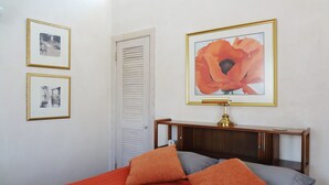 A bedroom with a bed, two framed pictures, a nightstand, and a lamp. - Artist Retreat in the Heart of Plaza (Taos)