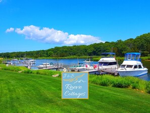 Un port de plaisance avec des bateaux amarrés, une zone herbeuse et un panneau indiquant l’emplacement des « J&S Reeves Cottages ».