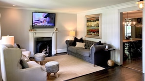 Una sala de estar con chimenea, televisor, un cuadro y un comedor.