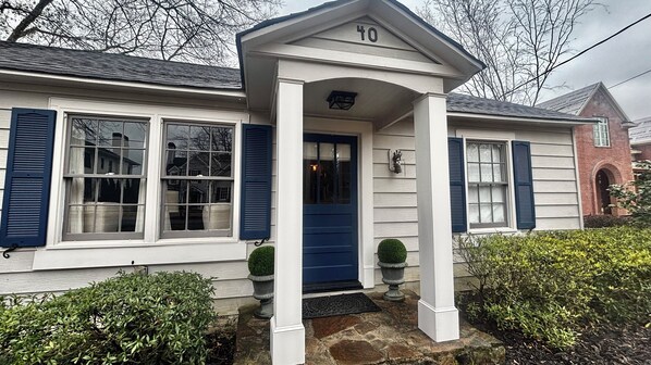Une maison avec une porte d’entrée bleue, un revêtement extérieur blanc et des volets bleus.